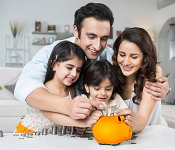 An Indian family saving money together in a piggy bank at home